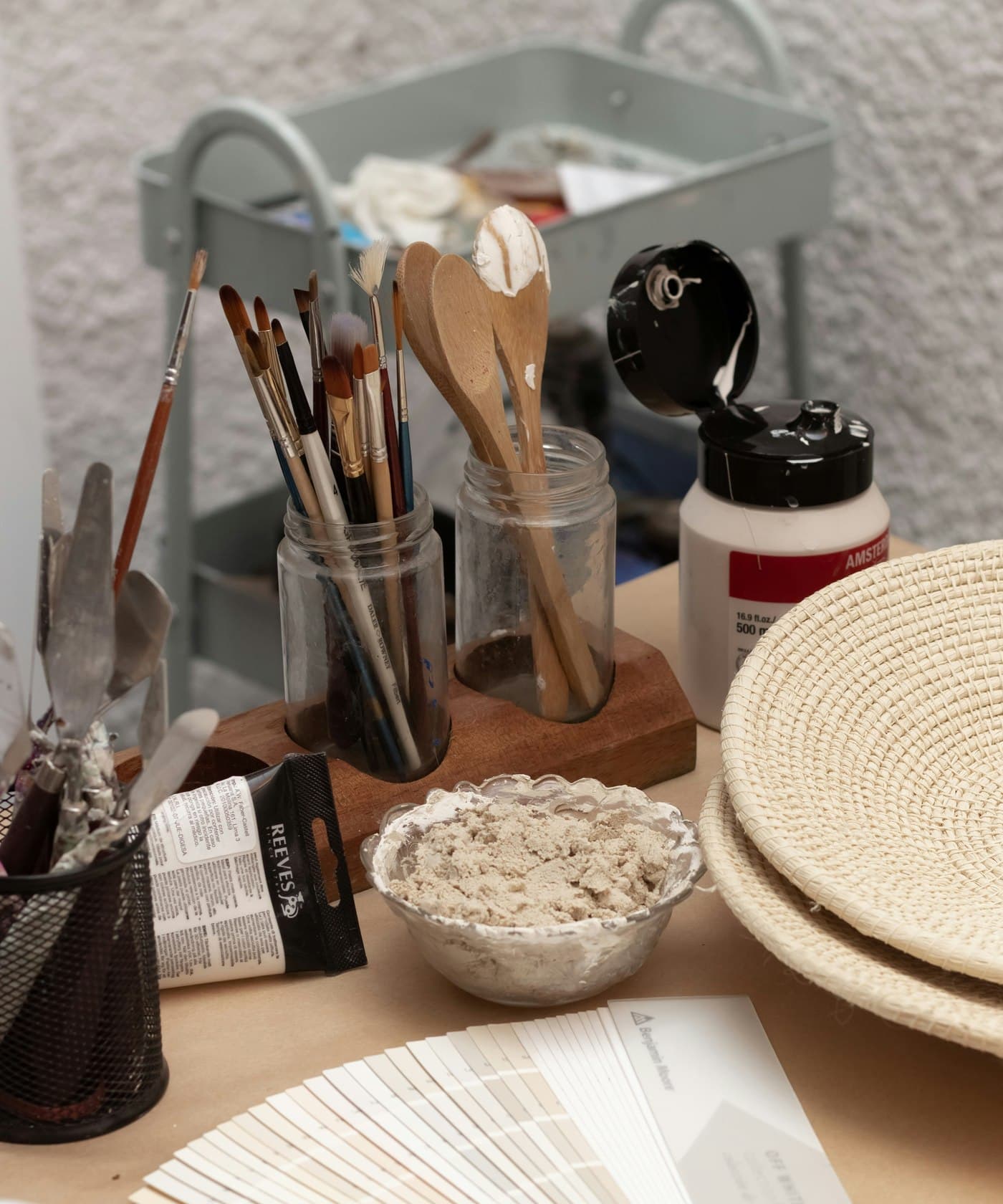 Mesa de ateliê com canecas, pincéis e materiais de personalização